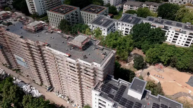 Drohnenaufnahme der Flachdachsanierung in Berlin-Buckow: eingerüstetes Wohnhochhaus, Team der ROB Abbruch GmbH auf dem Flachdach