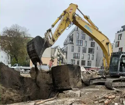 Abbruchbagger beim Gebäudeabriss in Berlin vor Neubauten