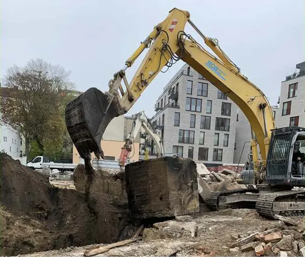 Abbruchbagger beim Gebäudeabriss in Berlin vor Neubauten