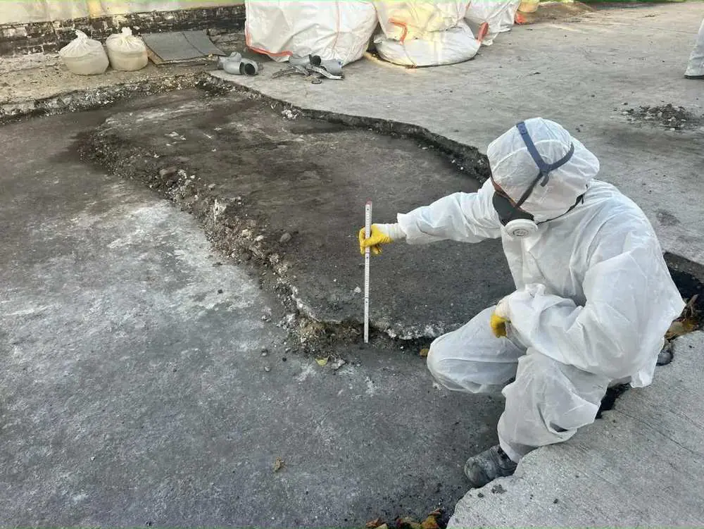 Asbestsanierung: Fachkraft im Schutzanzug prüft eine belastete Bodenfläche